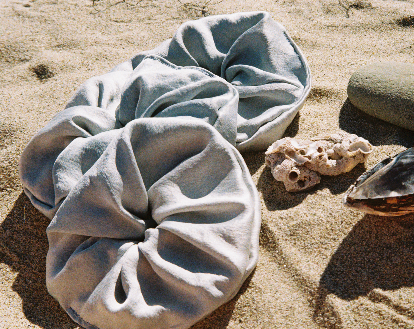 Three silk blue scrunchies dyed with indigo on the beach