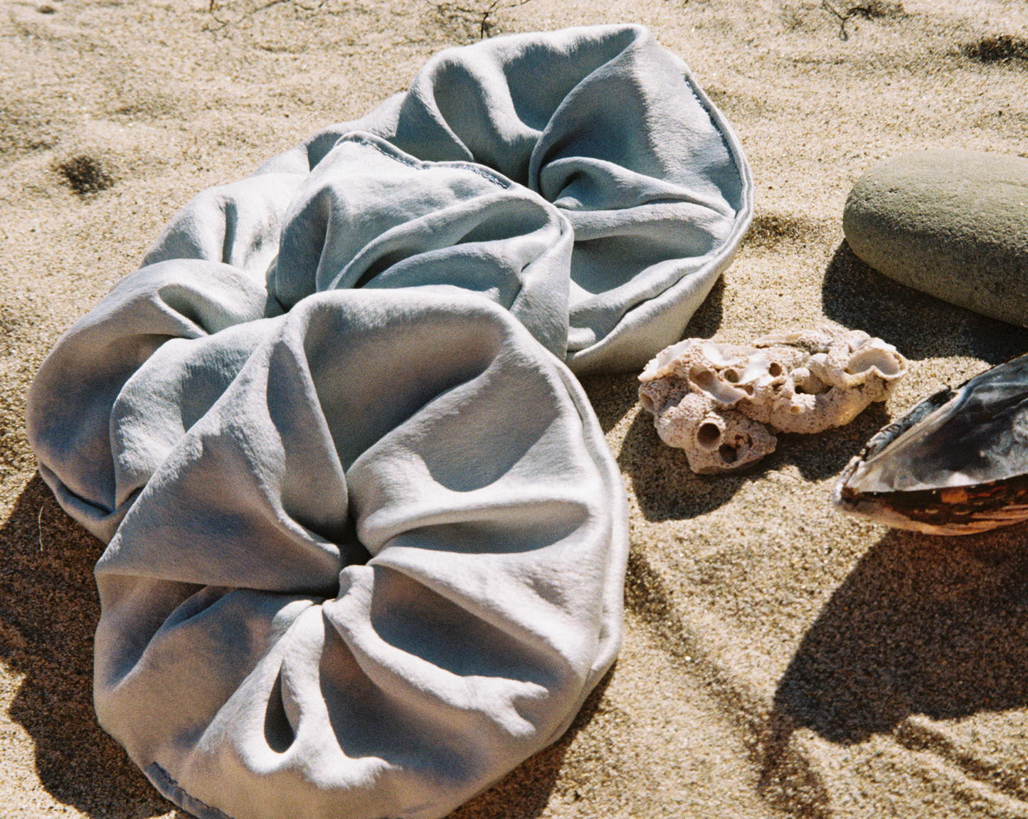 Three silk baby blue scrunchies on the beach