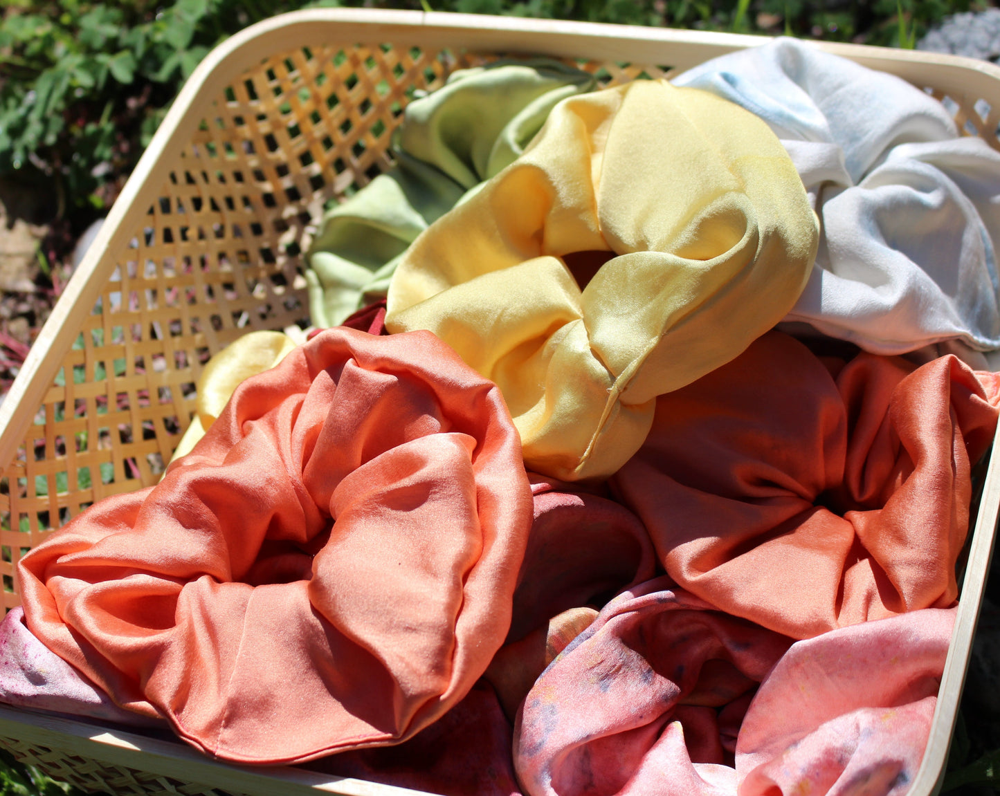 Peach silk scrunchie laying in a bed of silk plant dyed scrunchies