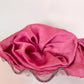 Goose Summer is a small, sustainable plant dyeing business making naturally dyed silk scrunchies and other accessories in Los Angeles. Two fuchsia plant dyed silk scrunchies displayed in a glass seashell bowl.