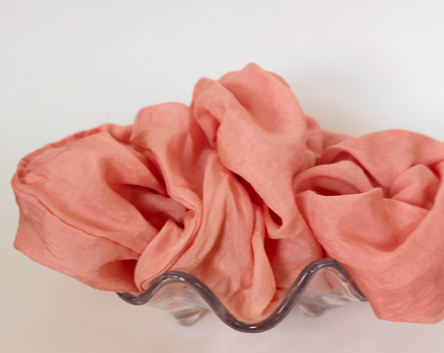 Goose Summer is a small, sustainable plant dyeing business making naturally dyed silk scrunchies and other accessories in Los Angeles. Pink Silk scrunchies in a clear seashell bowl.