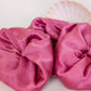 Goose Summer is a small, sustainable plant dyeing business making naturally dyed silk scrunchies and other accessories in Los Angeles. Three fuchsia colored silk scrunchies plant dyed by Goose Summer.