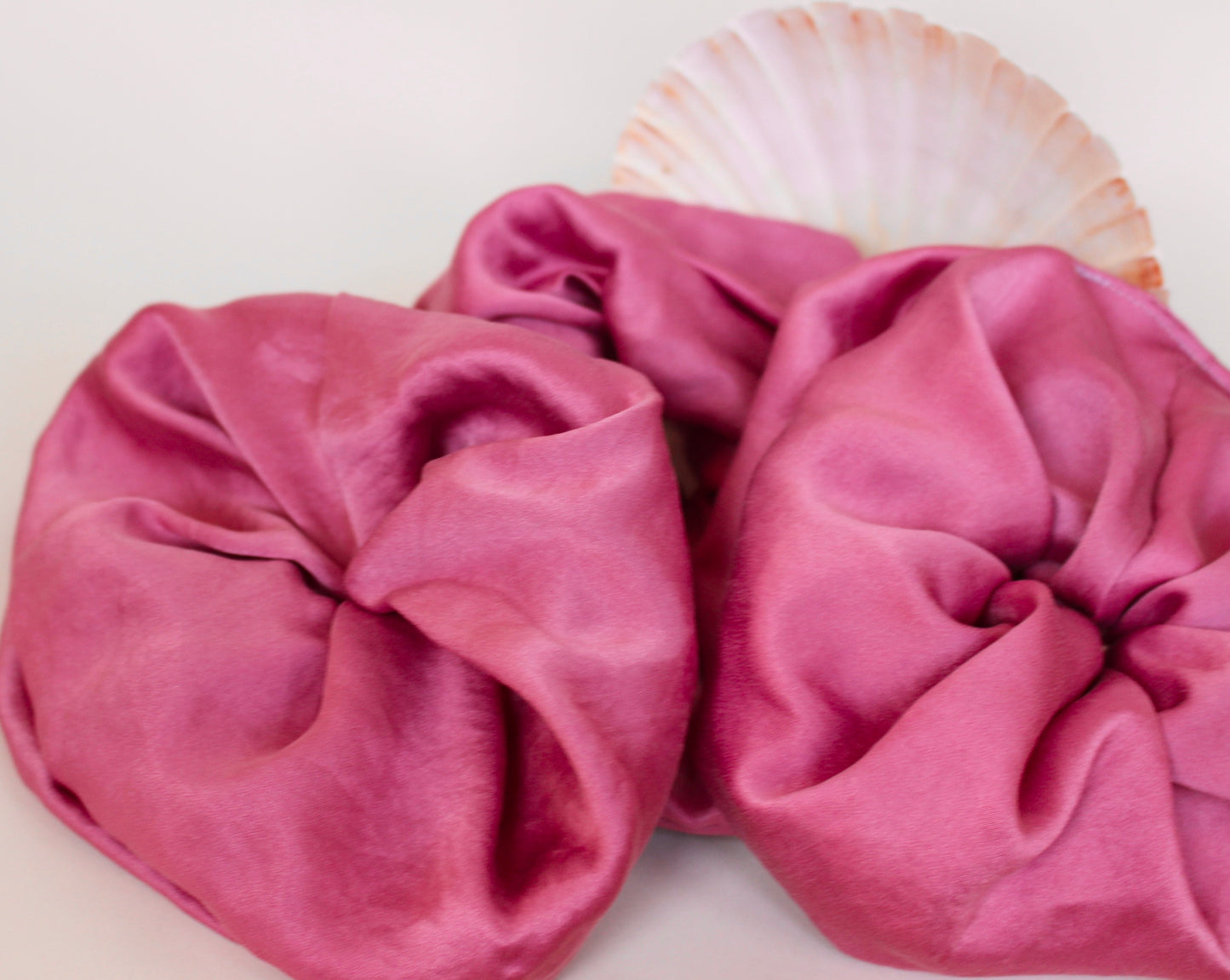 Goose Summer is a small, sustainable plant dyeing business making naturally dyed silk scrunchies and other accessories in Los Angeles. Three fuchsia colored silk scrunchies plant dyed by Goose Summer.