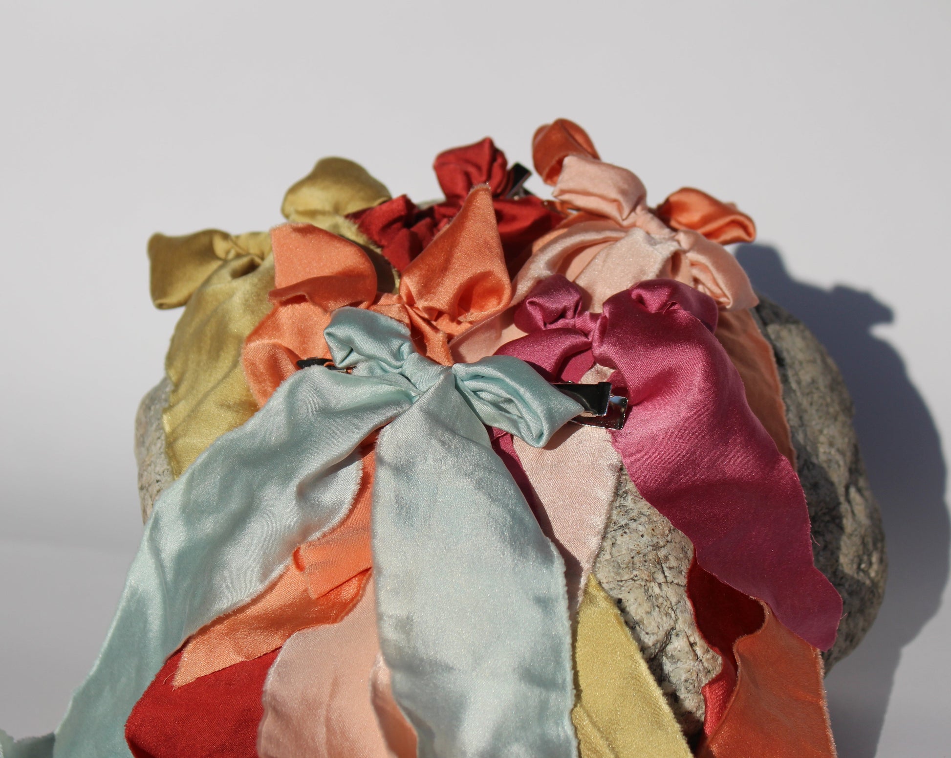 Six silk bows in all different colors laying flat on a rock