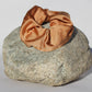 Cinnamon colored silk scrunchie on a rock