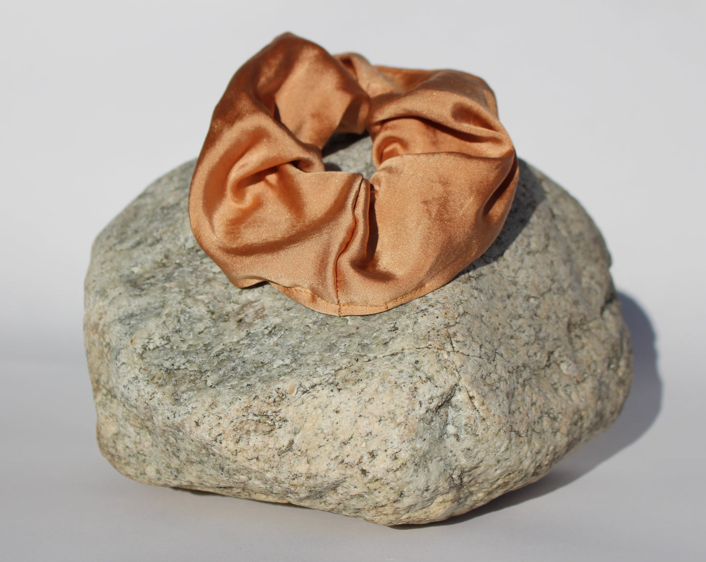 Cinnamon colored silk scrunchie on a rock