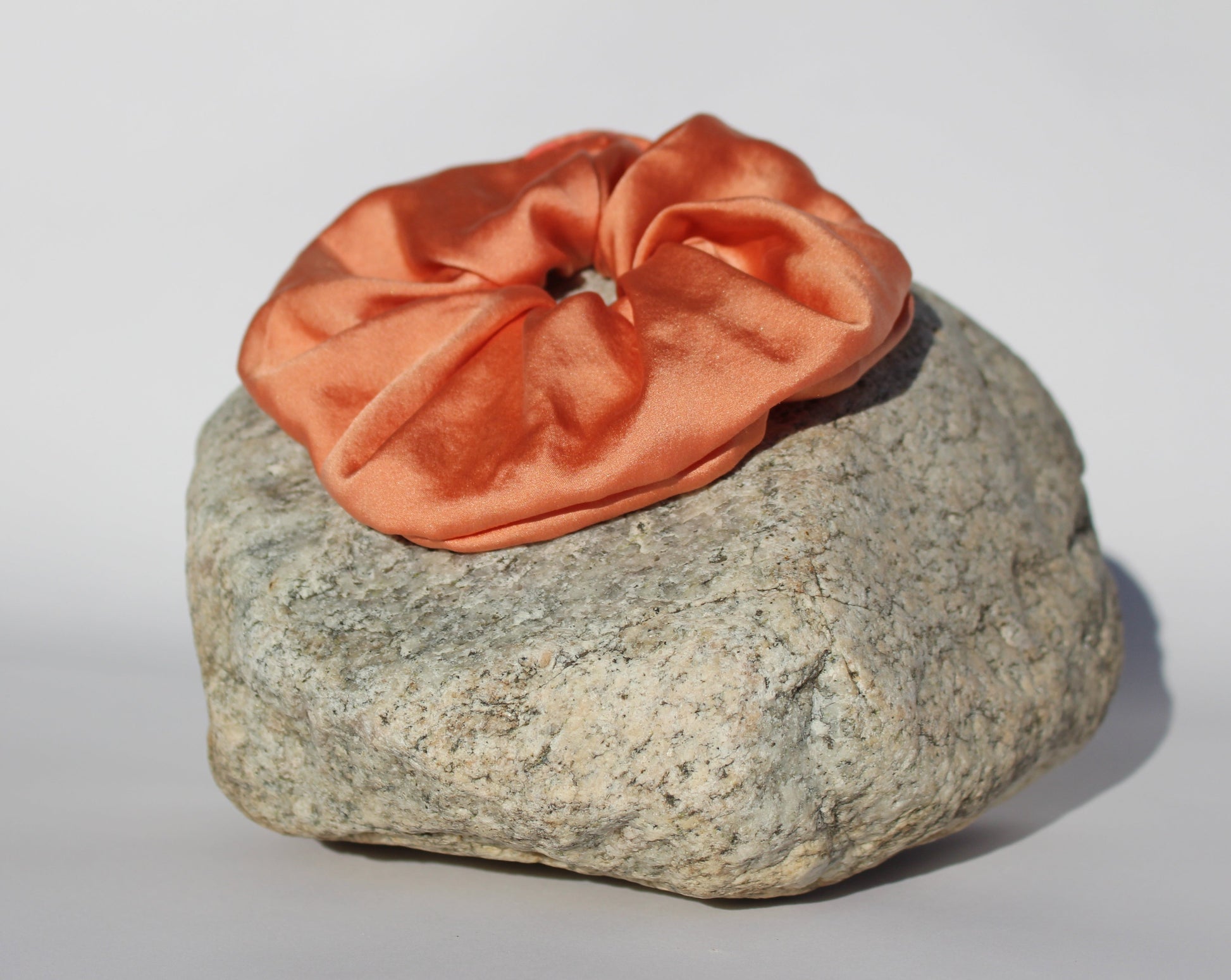 Peach colored silk scrunchie on a rock