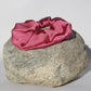 Silk Raspberry colored scrunchie on a rock