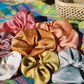 Rainbow Set of silk plant dyed scrunchies on a beach towel on the beach