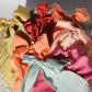 Six silk bows in all different colors laying flat on a rock