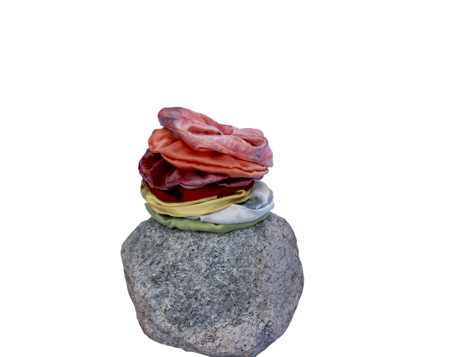 Rainbow set of silk scrunchies stacked on a rock