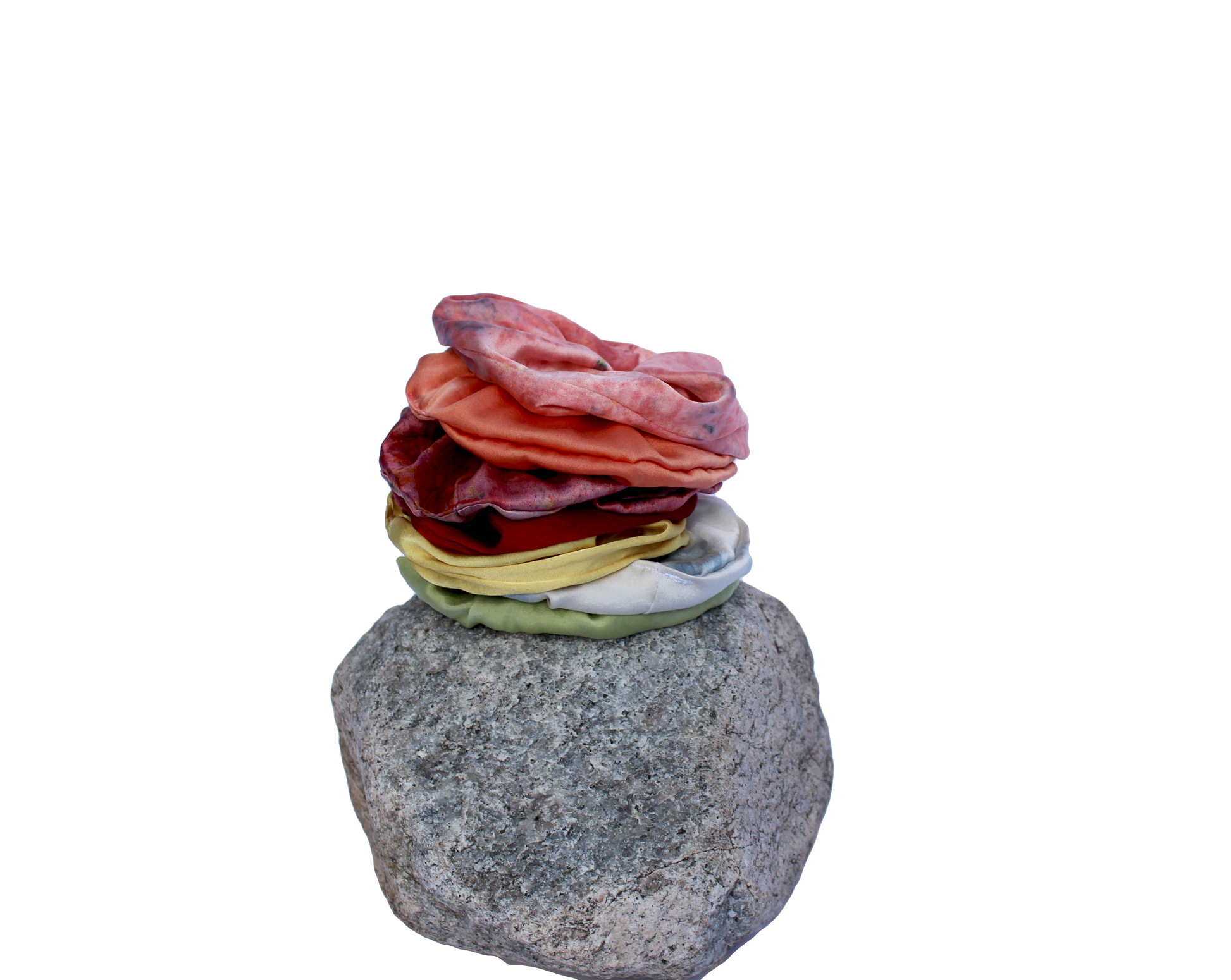 Rainbow set of silk scrunchies stacked on a rock