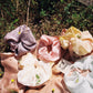 Five plant dyed silk scrunchie are laying in a field of grass. Hand made my Goose Summer Plant Dyes.Goose Summer is a small, sustainable plant dyeing business making naturally dyed silk scrunchies and other accessories in Los Angeles. 