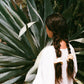 Woman standing in front of a agave plant with her beautiful dark brown hair tied in two braids with soft yellow silk scrunchies dyed with local eucalyptus found around LA. Goose Summer's Honey silk scrunchies are dyed with eucalyptus. Goose Summer is a small, sustainable plant dyeing business making naturally dyed silk scrunchies and other accessories in Los Angeles. 